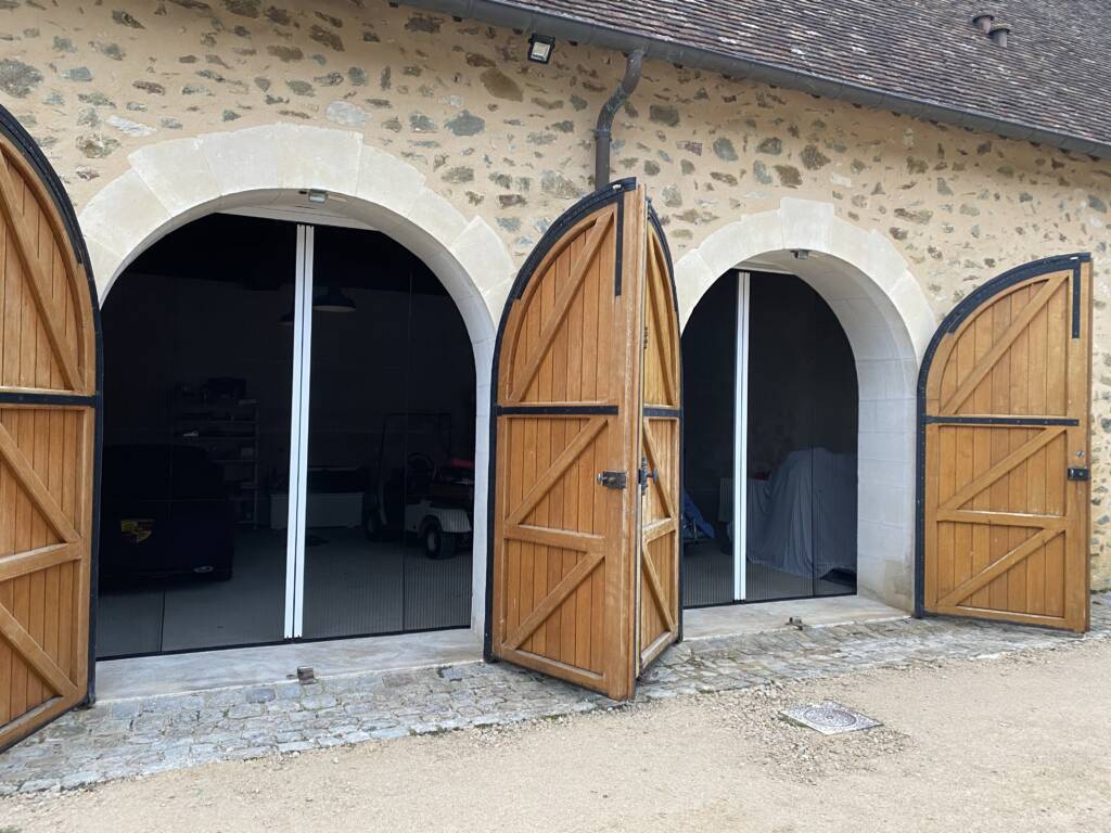 Moustiquaires doubles plissées portes pour protéger les voitures dans le garages (oiseaux). Quand le moderne s'intègre parfaitement à la chaleur de la pierre.